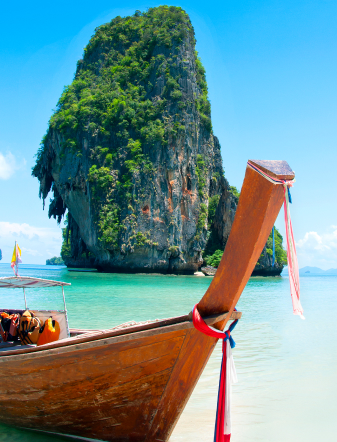 Traditional longtail boat below a limestone cliff, Thailand