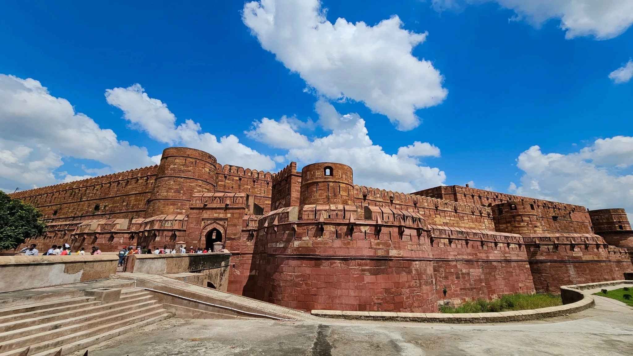 Red sandstone ramparts of Agra Fort under a blue sky with clouds