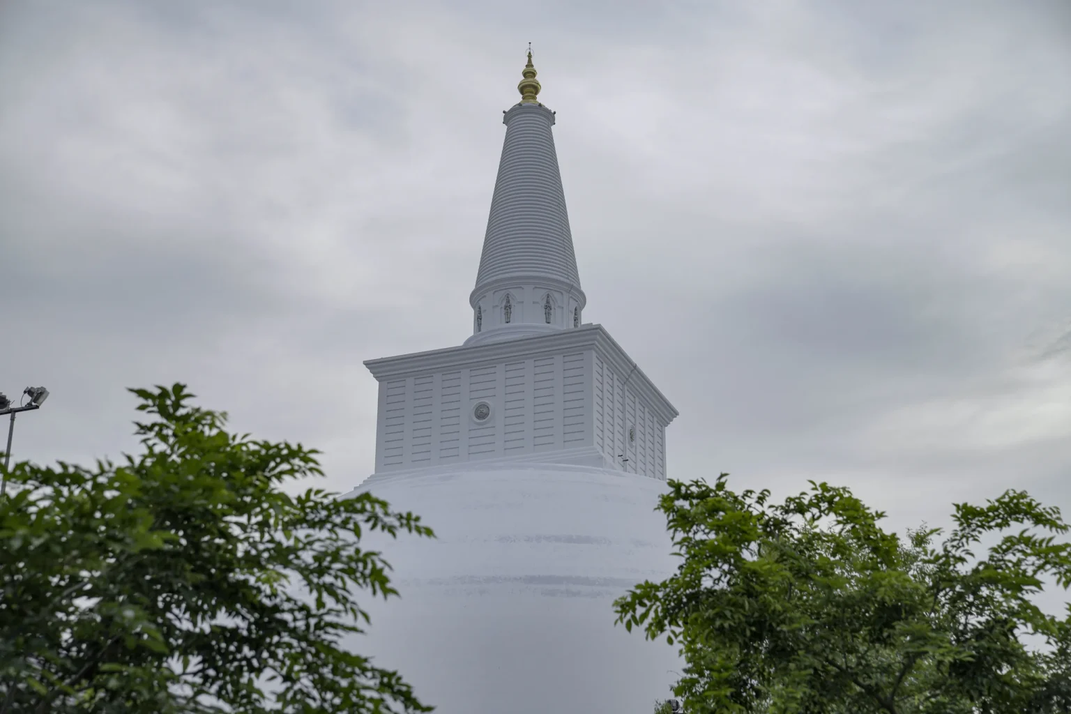 White spire of Ruwanwelisaya stupa framed by trees, Anuradhapura