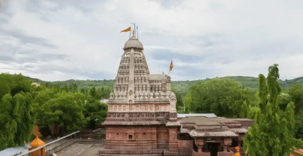 Ghrishneshwar Jyotirlinga temple with its tall carved spire among green trees, near Aurangabad
