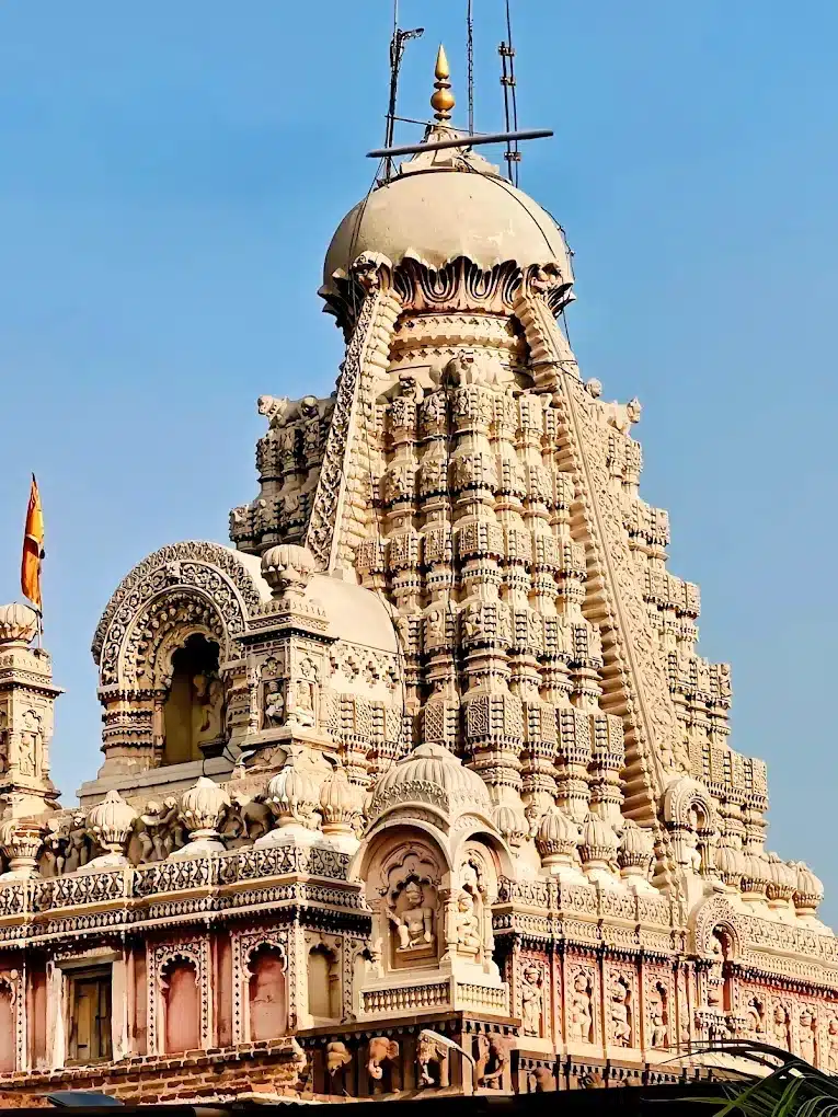 Carved stone spire of the Ghrishneshwar Jyotirlinga temple near Aurangabad, against a blue sky