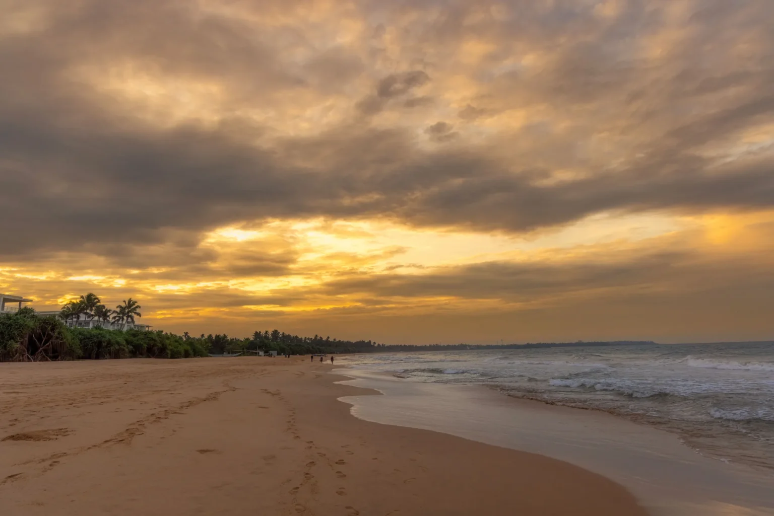 Empty Bentota beach under a golden sunset sky