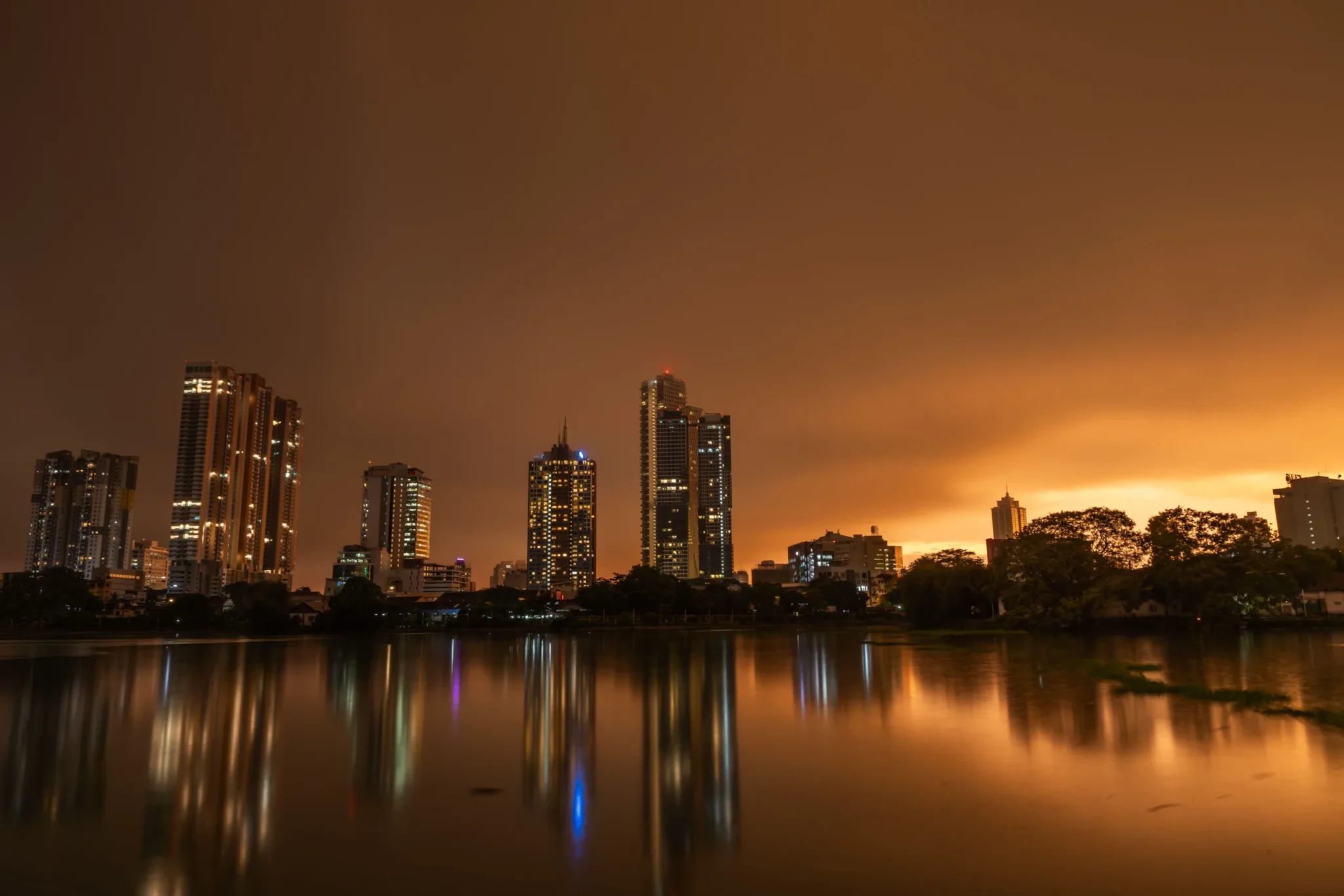 Colombo skyline reflected in Beira Lake at orange twilight