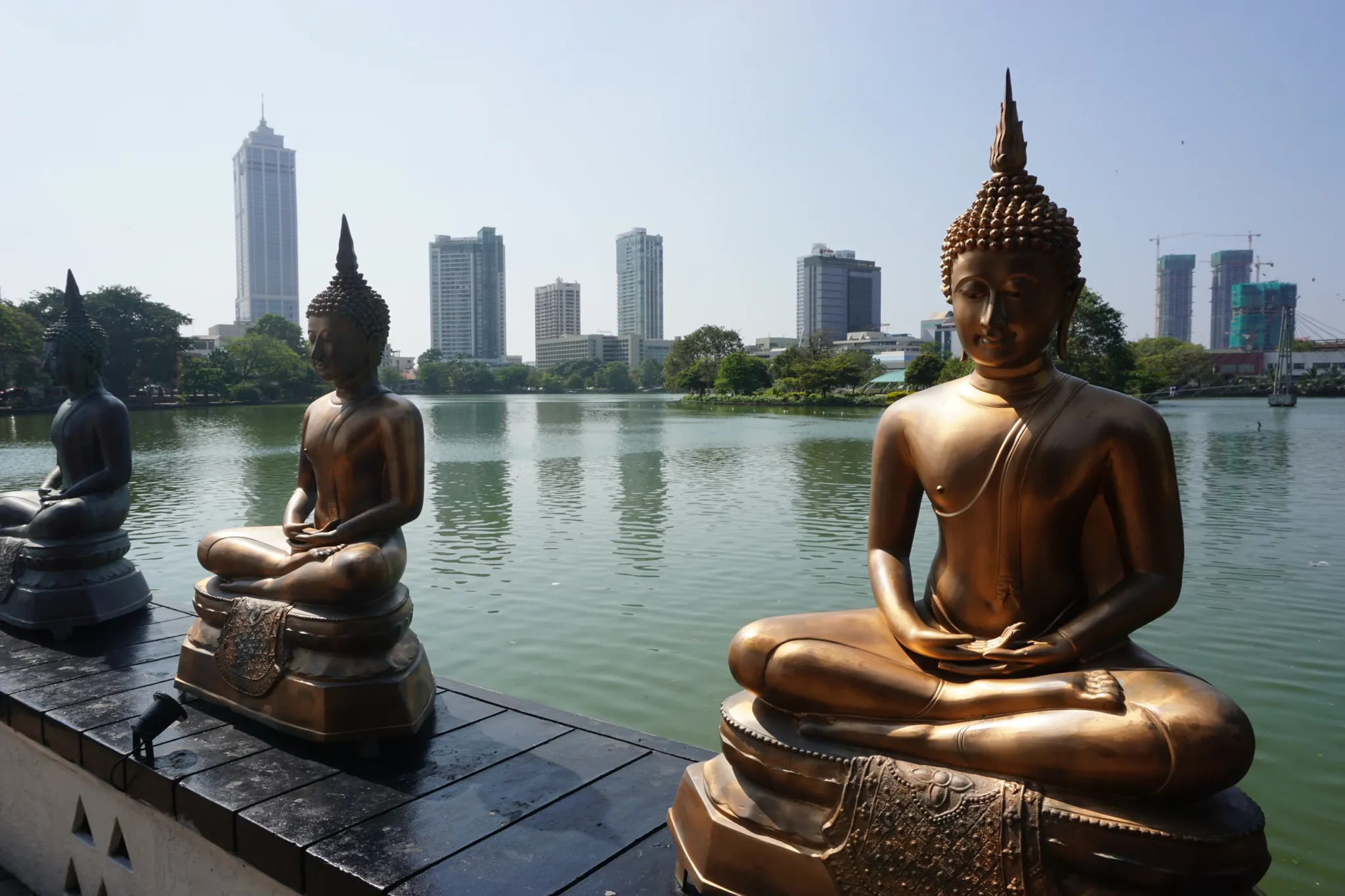 Buddha statues on Beira Lake with Colombo towers behind