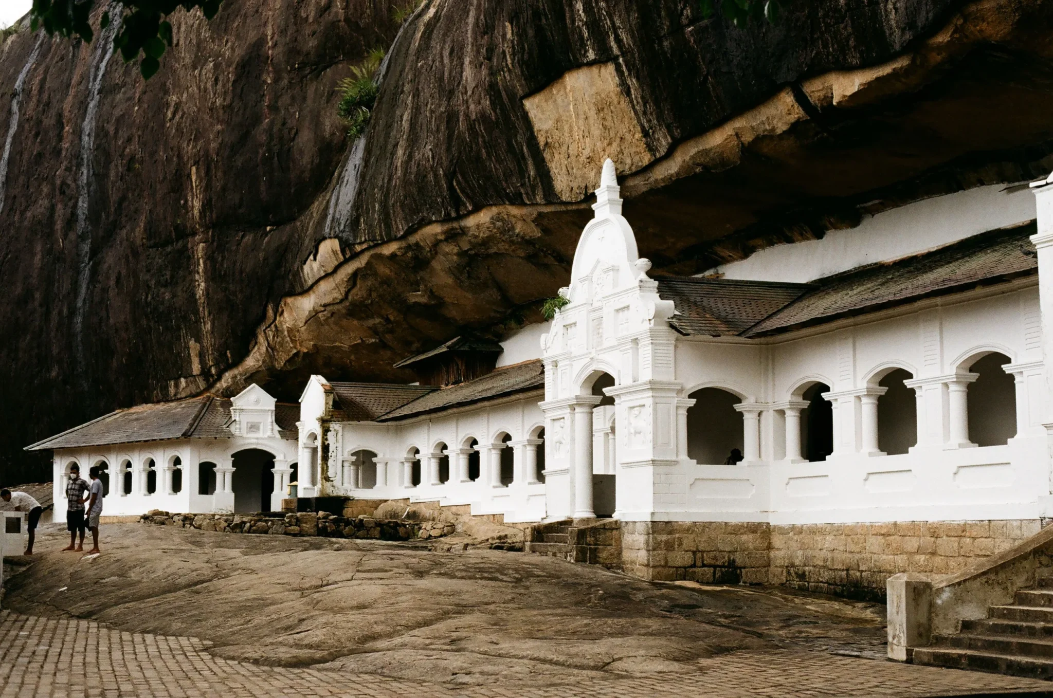 White facade of the Dambulla cave temple beneath the overhanging rock