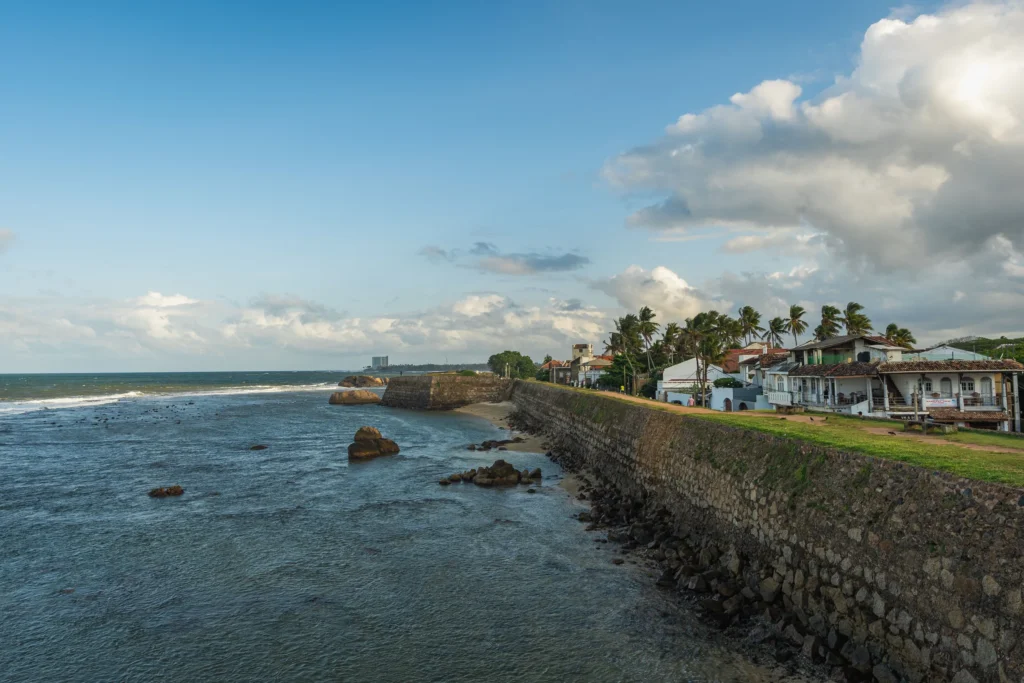 Galle Fort sea wall curving along the Indian Ocean under blue sky