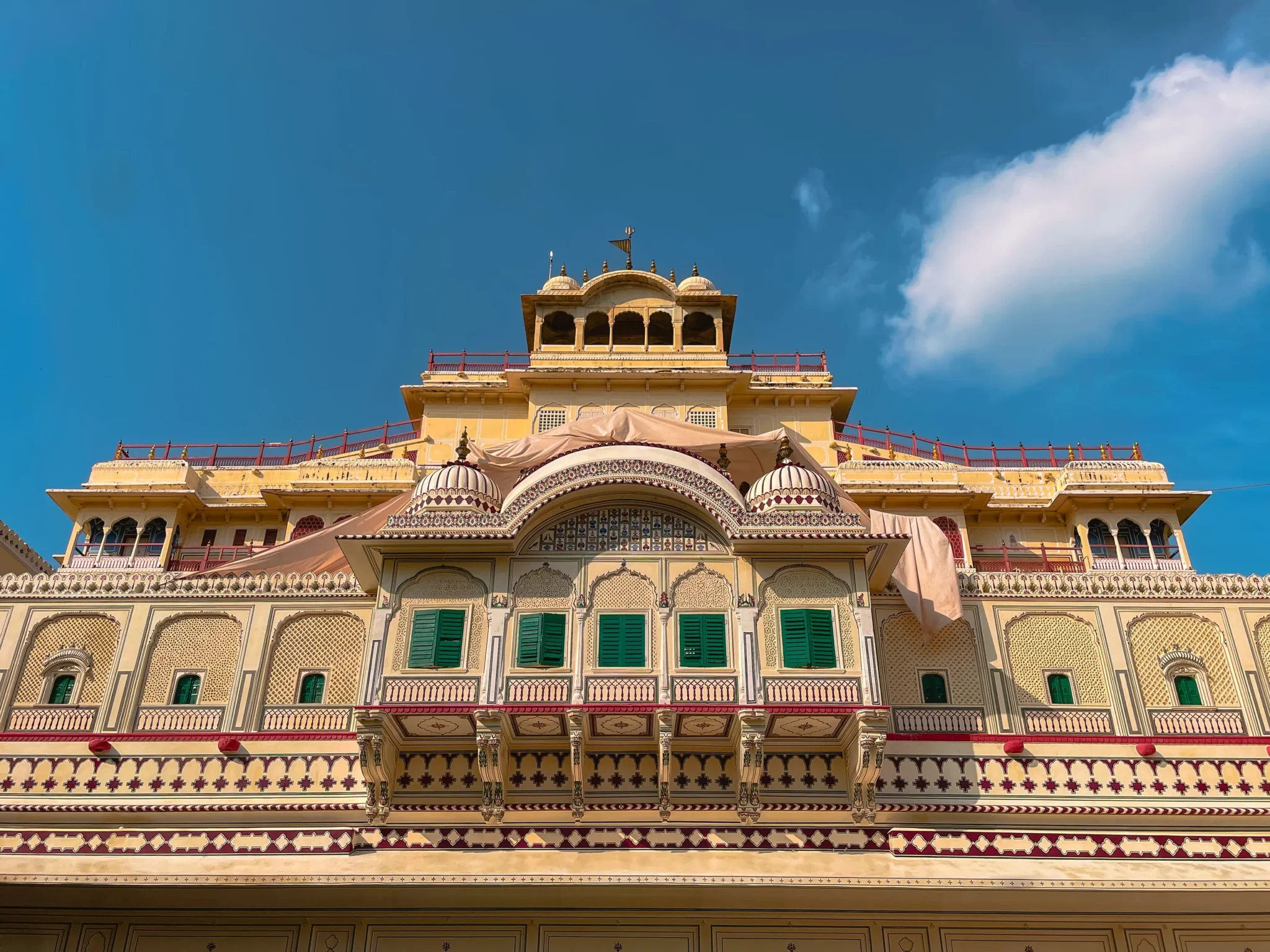 Ornate upper storeys of the City Palace, Jaipur, against a deep blue sky
