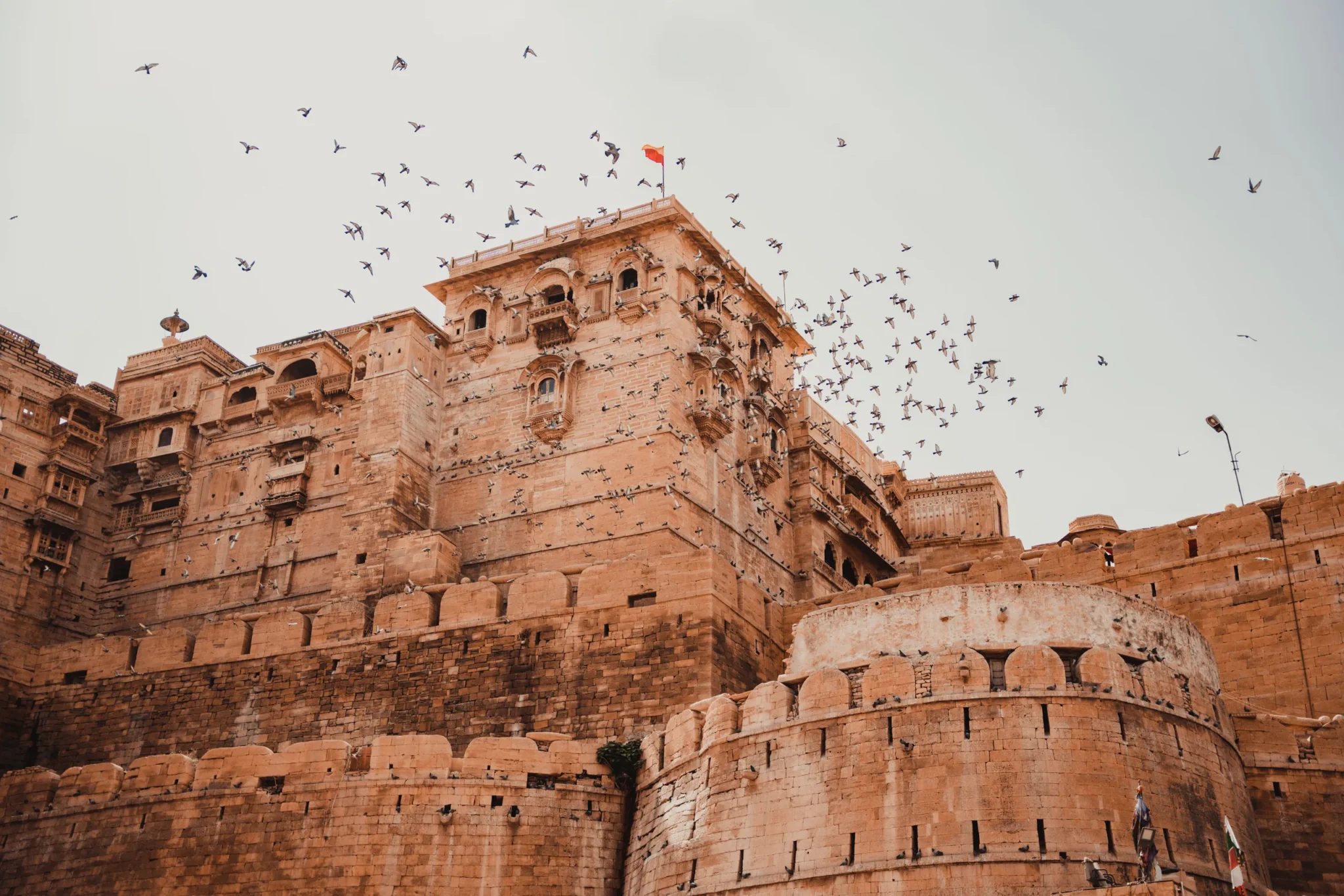 Sandstone bastions and palace of Jaisalmer Fort with birds overhead