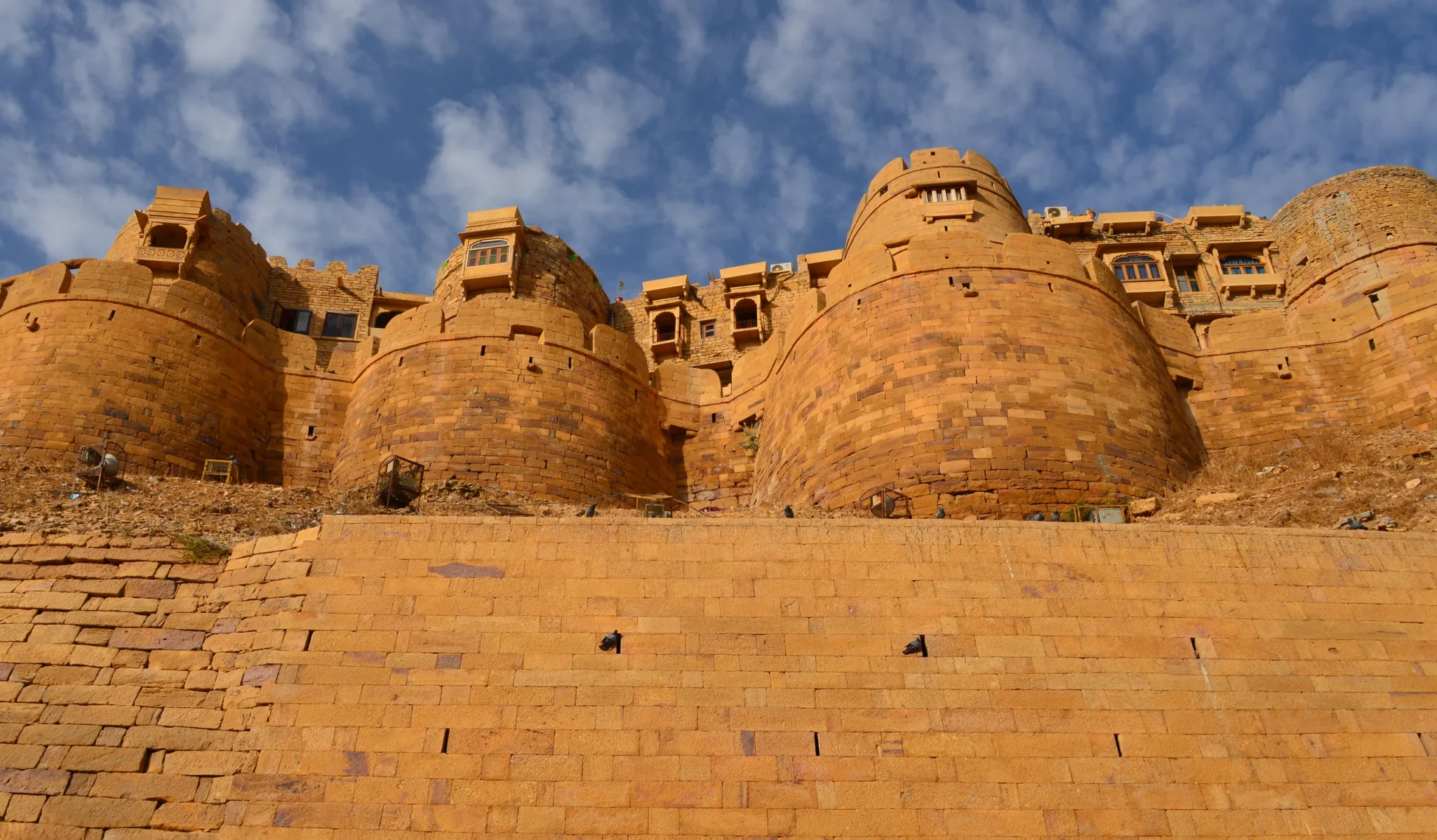 Rounded golden bastions of Jaisalmer Fort under a cloud-streaked blue sky