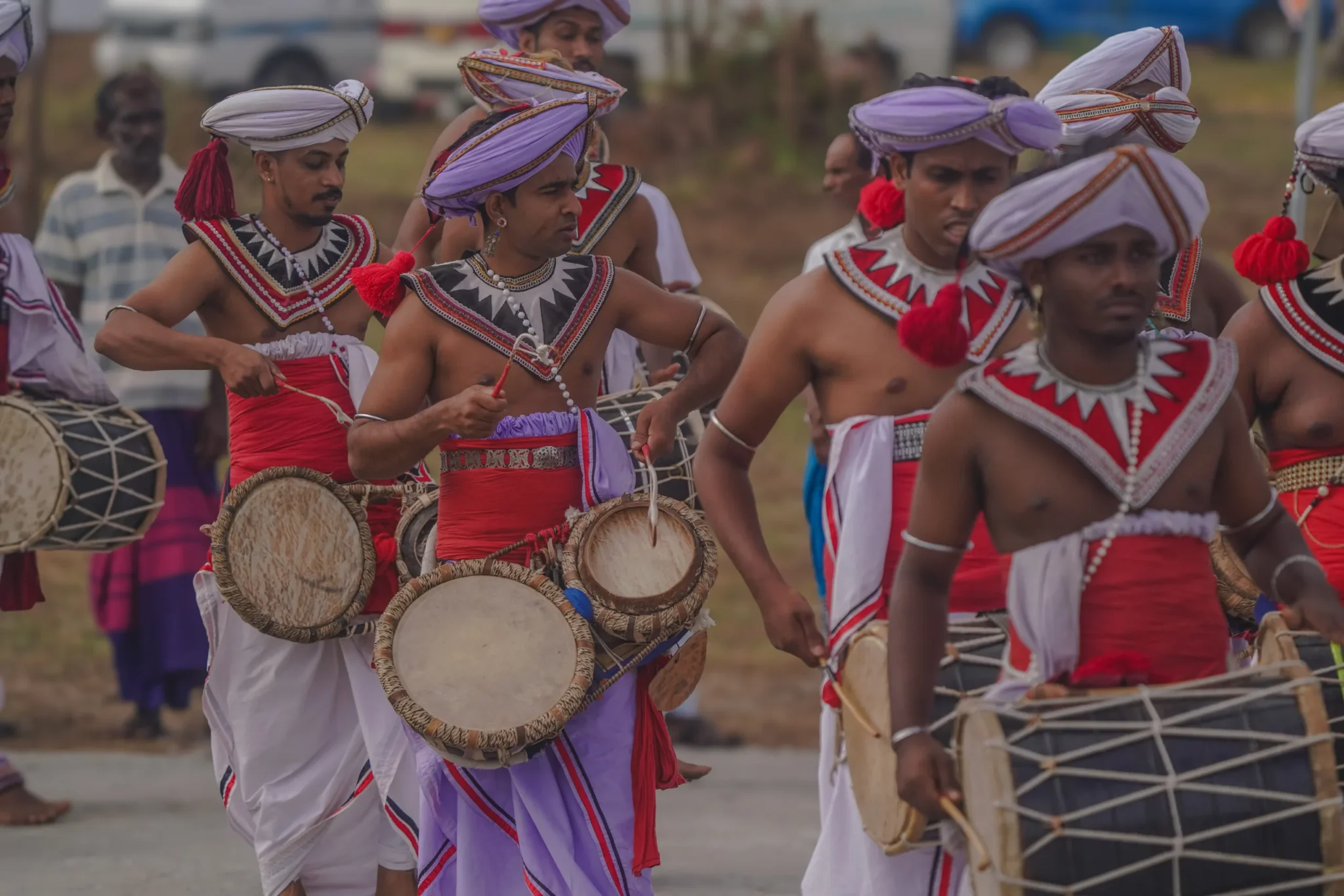 Kandyan drummers in red and white costume playing in procession