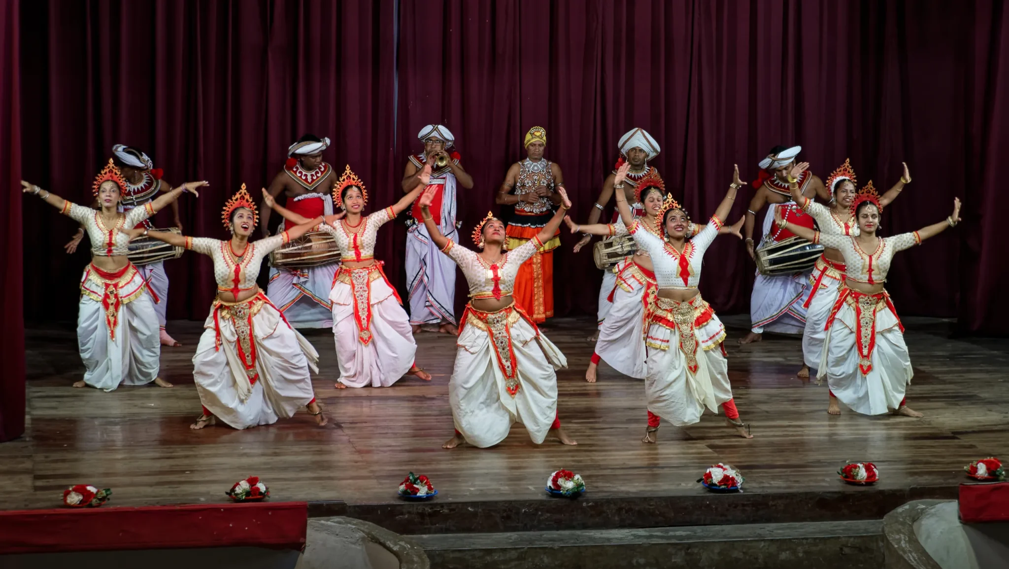 Kandyan dancers in white costumes performing on stage in Kandy