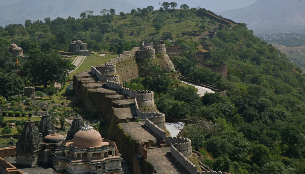 The great wall of Kumbhalgarh snaking over green hills above temples