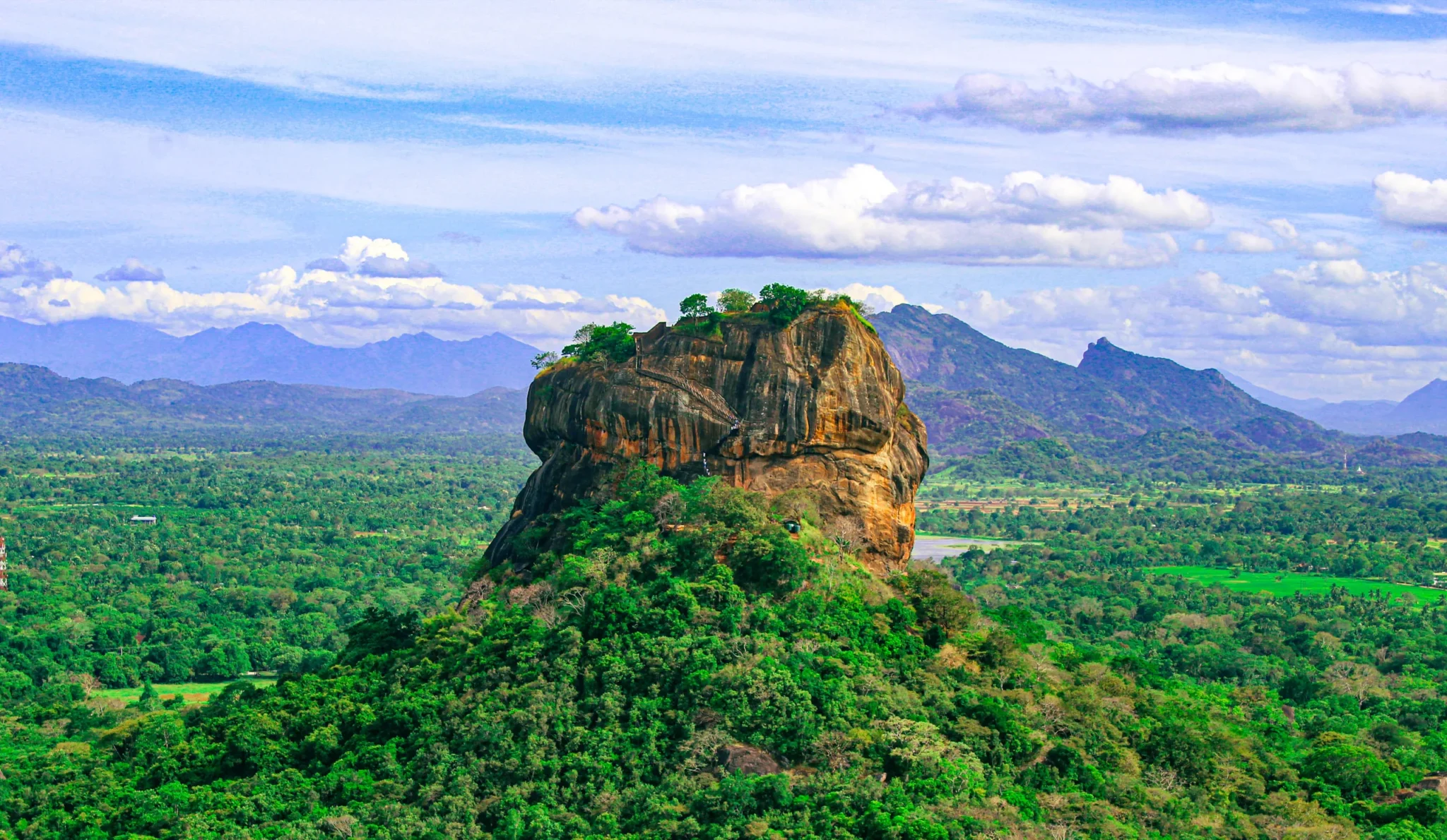 Sigiriya Rock Fortress above green forest under a blue sky